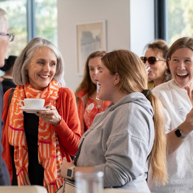 People smiling and talking at event.