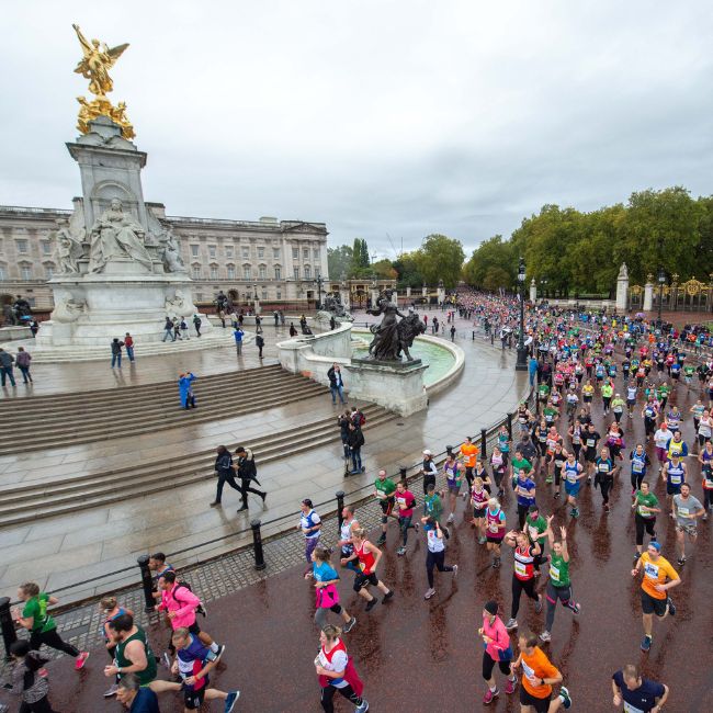 Runners in a race going past a statue in front of Buckingham Palace