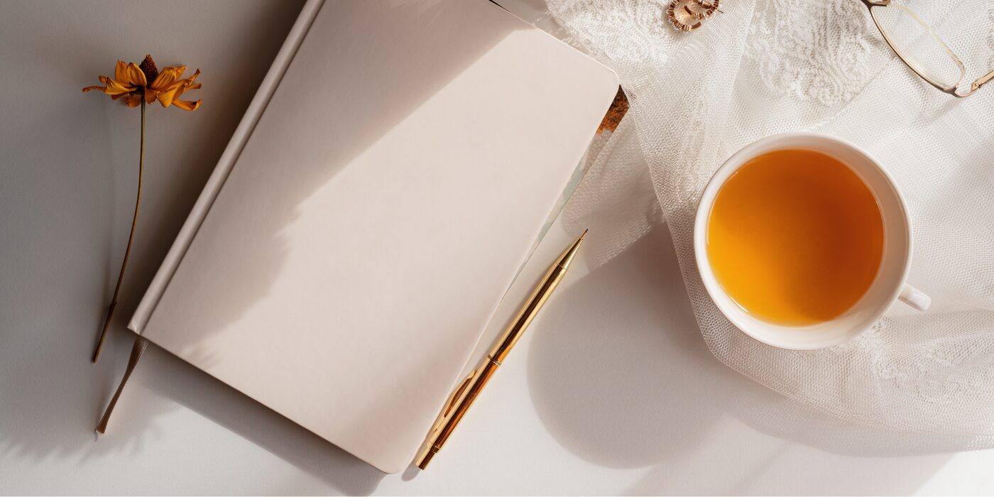 A journal, cup of tea and a flower