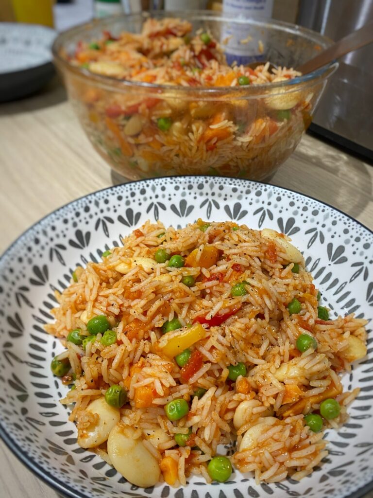A colourful plate of vegan jambalaya, consisting of rice, peas, butterbeans, tomatoes and spices.